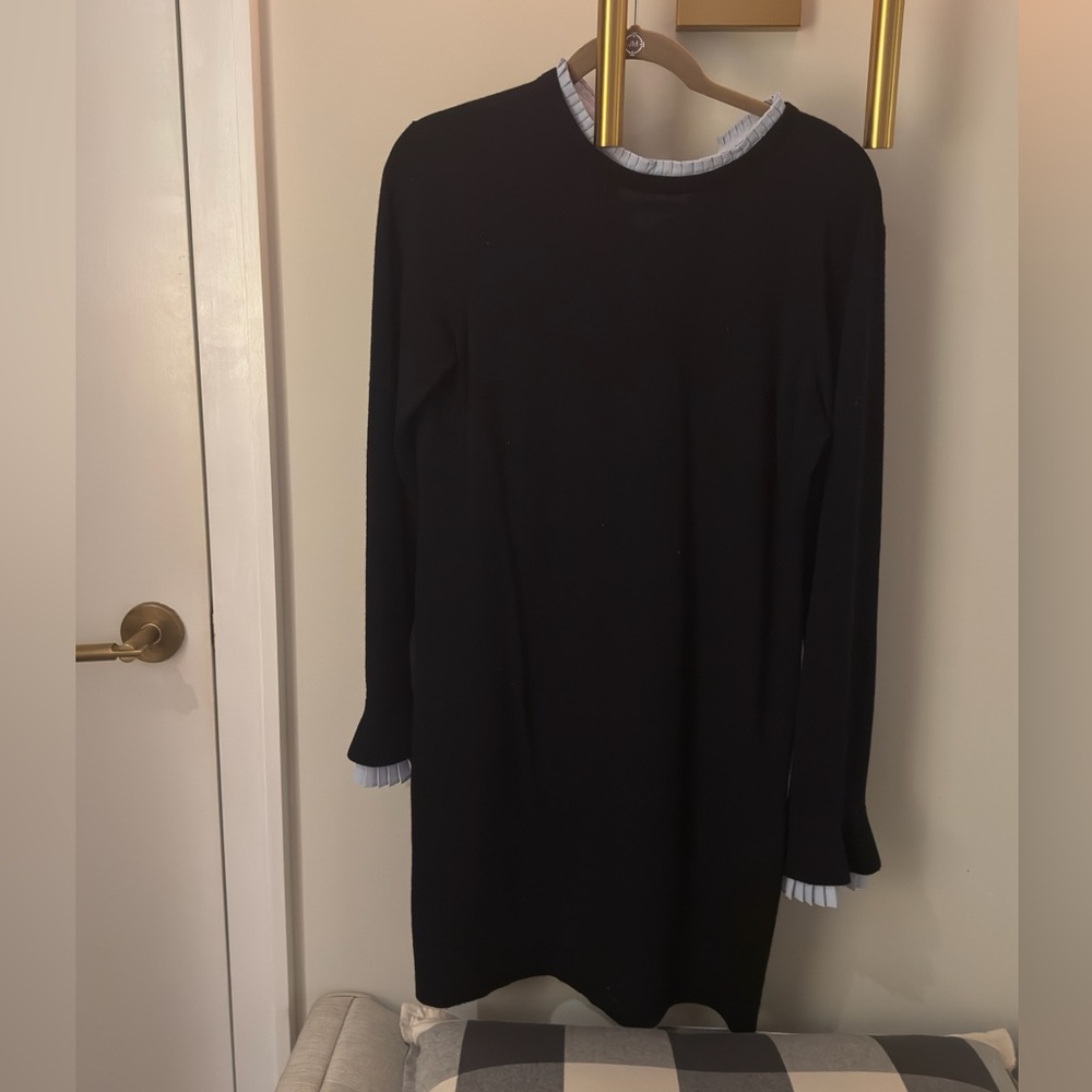 Black sweater mini dress with white ruffle detailing.